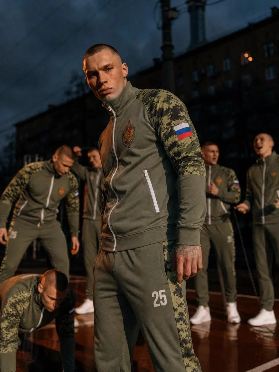 Команда в спортивных костюмах цвета хаки с камуфляжными вставками и флагом на рукаве